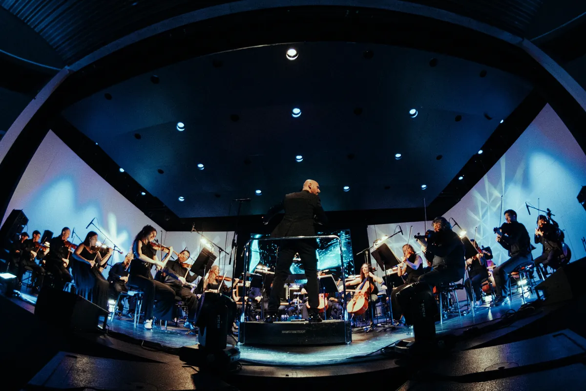 El director y la orquesta envueltos en luz azul